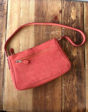 Sac en cuir velours terracotta, porté à l'épaule avec son anse et sa poche extérieure zippée