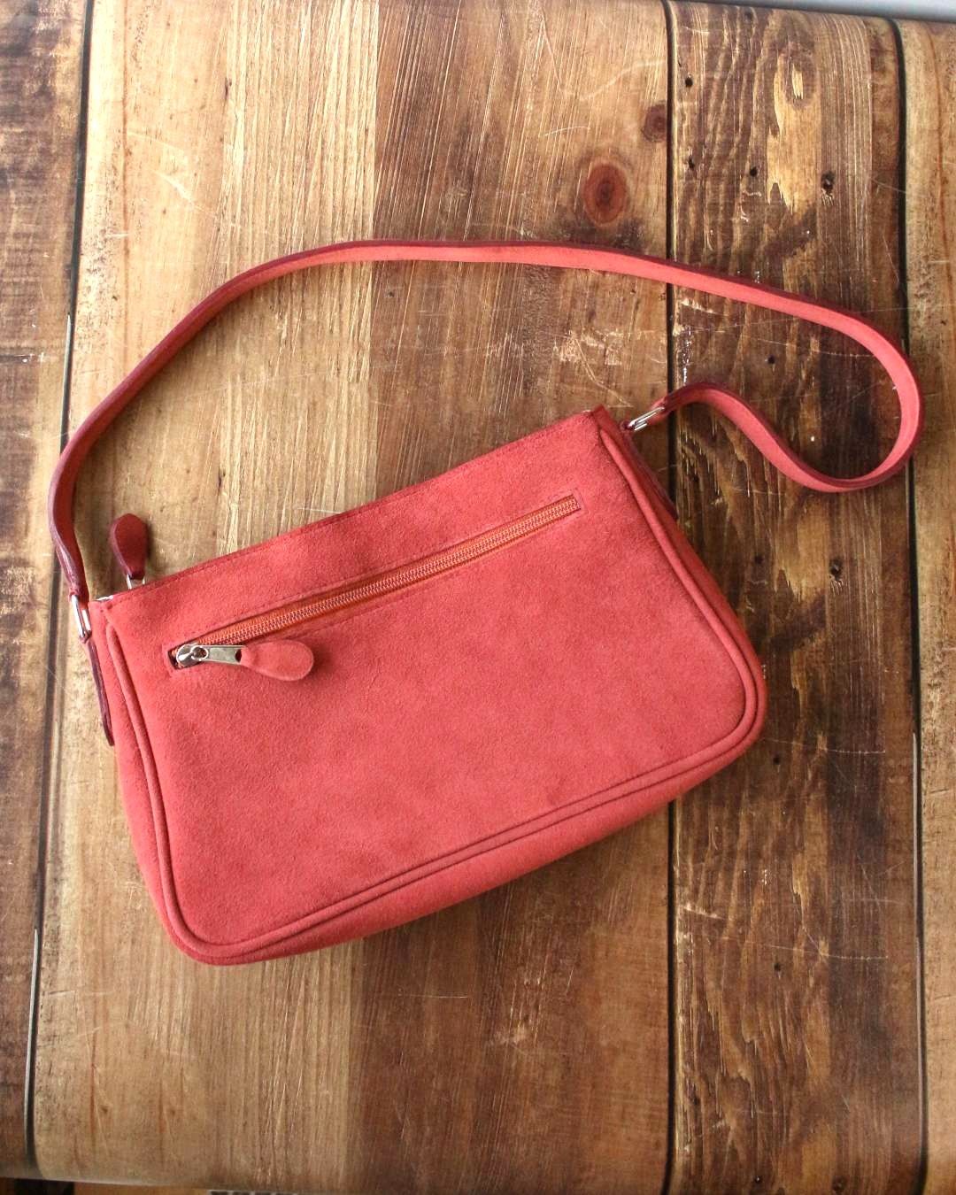 Sac-porte-a-lepaule-en-cuir Sac en cuir velours terracotta, porté à l'épaule avec son anse et sa poche extérieure zippée